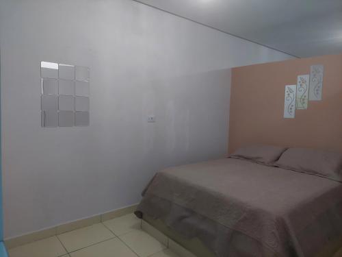 a bedroom with a bed and a white wall at Kitnet Vila Marcela in Petrolina
