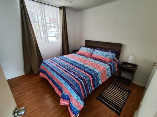 1 dormitorio con 1 cama con manta y ventana en Arriendo Departamento Diario en Copiapó, en Copiapó