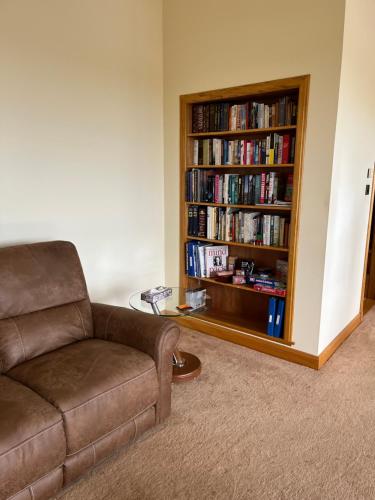 una sala de estar con sofá y una estantería llena de libros. en Apartment 500 - Metro style apartment on NC500 en Thurso