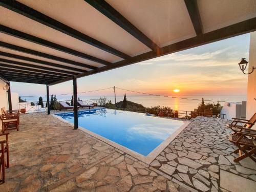 a villa with a swimming pool and a sunset at Villa Ioanna in Kalamitsi