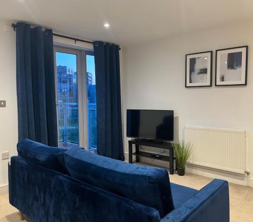 a living room with a blue couch and a television at Beautiful Riverview Apartment Chelmsford in Chelmsford