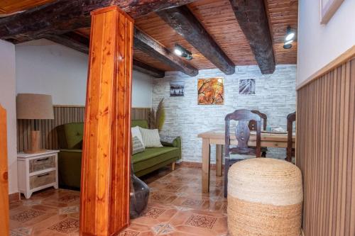 Casa Rural El Burrito de Gredos في Pedro Bernardo: غرفة معيشة مع طاولة وأريكة خضراء