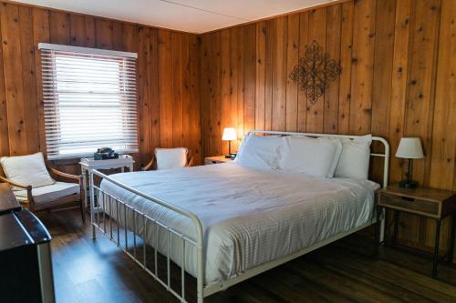1 dormitorio con 1 cama y pared de madera en Whispering Winds Motel, en Auburn
