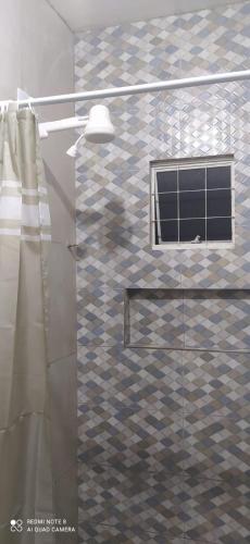 a bathroom with a glass shower with a window at Casa Confortável com Garagem e internet in Caruaru