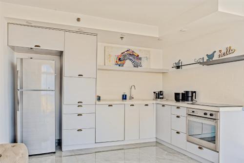 a white kitchen with white cabinets and a refrigerator at Orchid sea view apartment in Tel Aviv