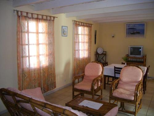ein Wohnzimmer mit Stühlen, einem Tisch und einem TV in der Unterkunft Villa Herifanja Antsirabe in Antsirabe