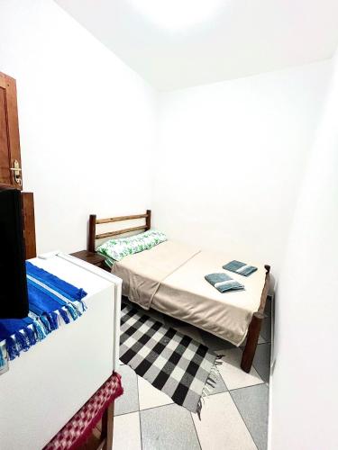 um pequeno quarto com uma cama e um piso em xadrez em Pousada Diniz em Resende