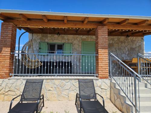 two chairs on a deck with a gate and a playground at Holiday house Adriana in Povljana