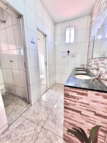 uma casa de banho com um lavatório e um chuveiro em Pousada Diniz em Resende