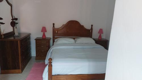 a bedroom with a bed and two dressers and two lamps at Casita do jardim in Ponte de Lima