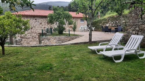 two white chairs sitting in the grass in a yard at Casita do jardim in Ponte de Lima