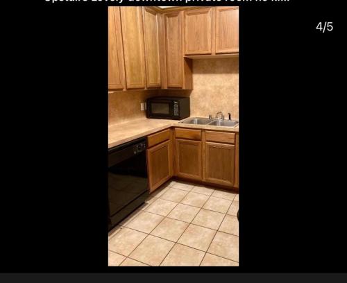 eine Küche mit Holzschränken, einer Spüle und einer Mikrowelle in der Unterkunft Sweet Downtown Room #1 second floor no smoking no kids in Houston