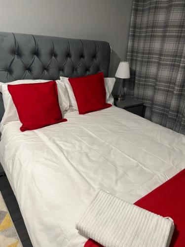 a large bed with two red pillows on it at Mona's Home in Dagenham