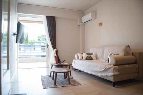 a living room with a couch and a tv at Naiads Nest - The Cozy Retreat in Varkiza