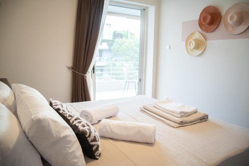 1 dormitorio con 1 cama con toallas y ventana en Naiads Nest - The Cozy Retreat, en Varkiza