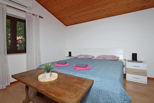 1 dormitorio con cama azul y mesa de madera en Rooms with WiFi Brsec, Opatija - 7768, en Brseč
