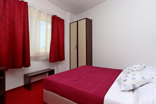 una camera da letto con lenzuola rosse e tende rosse di Apartments by the sea Selce, Crikvenica - 18195 a Selce