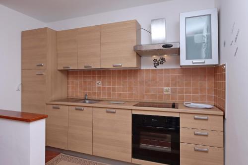 una cucina con armadi in legno, lavandino e forno a microonde di Apartments by the sea Selce, Crikvenica - 18195 a Selce