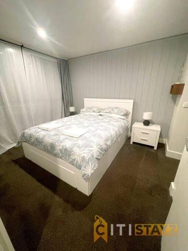 a bedroom with a white bed and a night stand at Braddon 1BD - Walk to Cafés, Secure Parking in Canberra