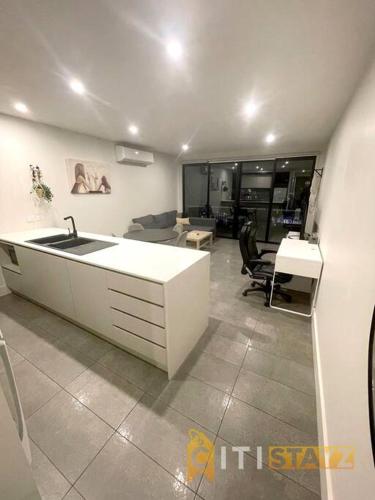 a kitchen with a sink and a living room at Braddon 1BD - Walk to Cafés, Secure Parking in Canberra