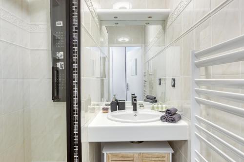uma casa de banho branca com um lavatório e um espelho em La vallée village centre Disneyland Paris em Serris