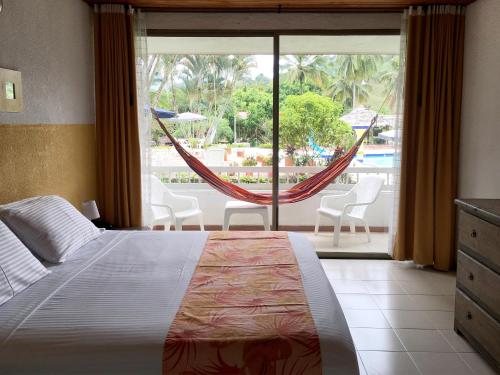 a bedroom with a bed and a window with a hammock at Hotel Hacienda El Diamante in Villeta