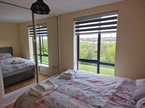 een slaapkamer met 2 bedden en een groot raam bij Clearwater Apartment in Dublin