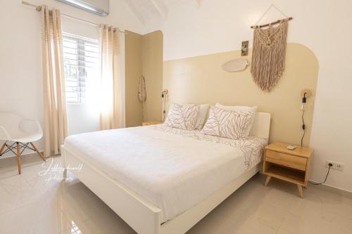 a white bedroom with a large bed with white sheets and pillows at Dushi Townhouse Curaçao in Willemstad