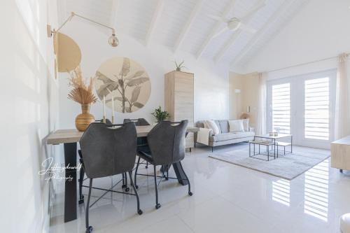 una sala de estar blanca con mesa y sillas en Dushi Townhouse Curaçao en Willemstad