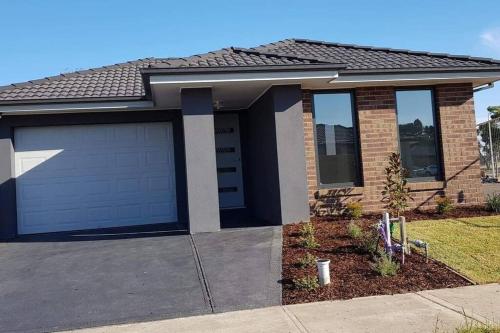 a house with a garage door and a driveway at Homely and newly built place with a lot to do. in Beaconsfield