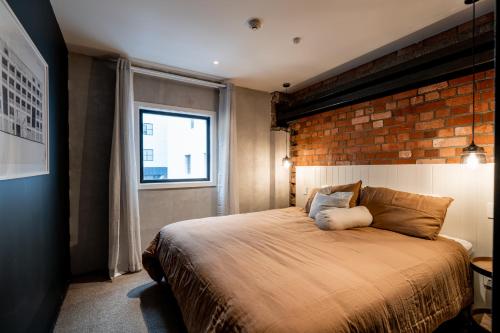 um quarto com uma cama grande e uma parede de tijolos em The Cobbler Hotel em Wellington