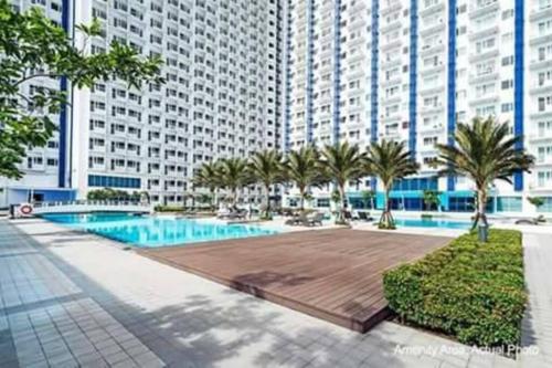 a large apartment building with a pool and palm trees at Cozy 1 Bedroom in Makati City in Manila