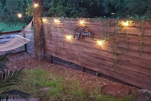 a fence with a hammock and lights on it at The Tiny 'Tainer - Tiny Container Home w. Hot Tub! in Weatherford