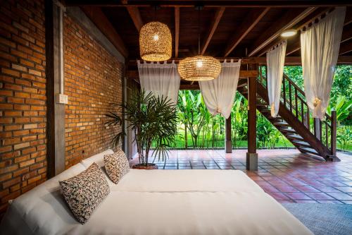 a bedroom with a white bed in a brick wall at Farmhouse Resort & Spa in Kampong Chhnang