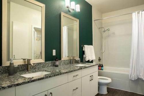 baño con 2 lavabos, aseo y pared verde en Modern SoCo CozySuites w 2 Pools #05 en Austin