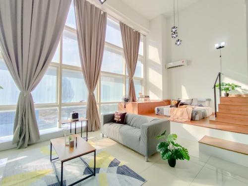 a living room with a couch and large windows at Empire City PJ Signature Suites by Manhattan Group in Petaling Jaya