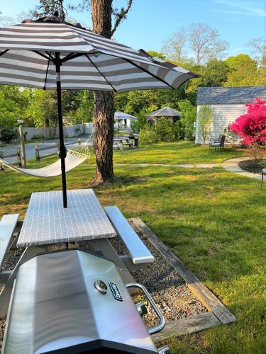 a picnic table with an umbrella in a park at The Seagrove Suites & Guest Rooms in Eastham