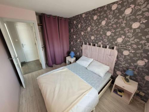 Schlafzimmer mit einem Bett mit Blumentapete in der Unterkunft Appartement Wimereux, 2 pièces, 2 personnes - FR-1-675-24 in Wimereux