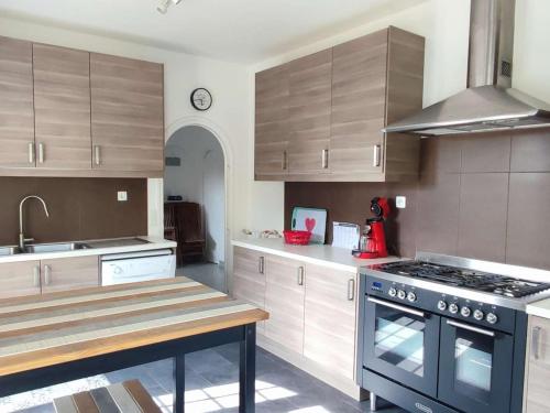 une cuisine avec des armoires en bois et un four à plaques de cuisson dans l'établissement Grande Maison Familiale à Trégastel avec Jardin Clos, Terrasse et WIFI - FR-1-368-393, à Trégastel