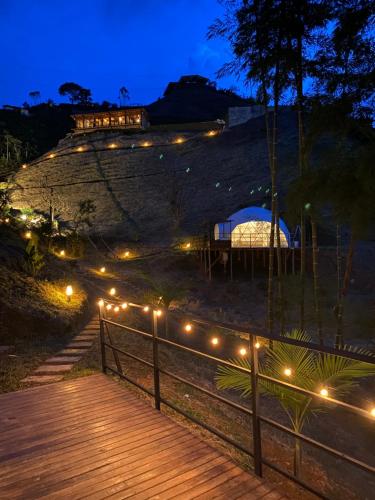 a boardwalk with lights on a hill at night at Elysium Glamping in Guatapé