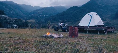 een man op een motor naast een tent en een brand bij La Bella Finca Hostal-Lodge in Villamaría