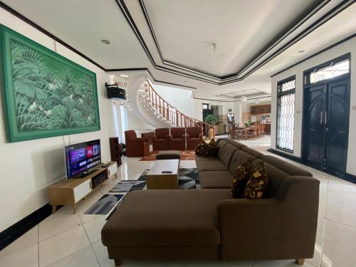 een woonkamer met banken, een televisie en een trap bij Villa Laura in Puncak