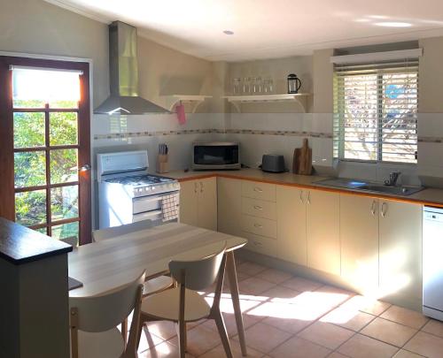 y cocina con mesa, sillas y fogones. en Willow Cottage, en Kurrajong