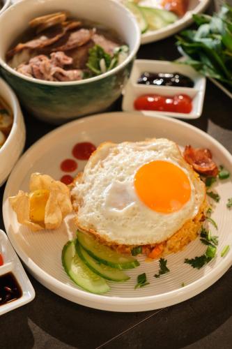 a plate of food with an egg on top at Tuong Boutique Resort Mui ne in Mui Ne