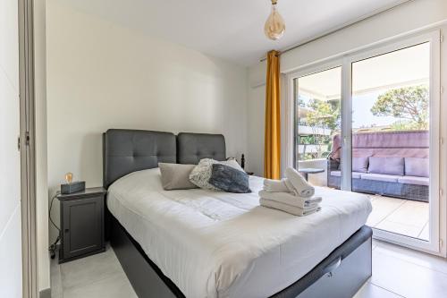 une chambre avec un grand lit et un balcon dans l'établissement Appartement climatisé les pieds dans l'eau pour 6 personnes avec 1 suite parentale, 1 chambre double et 1 mini chambre Piscine sur le toit clim garage, à Villeneuve-Loubet