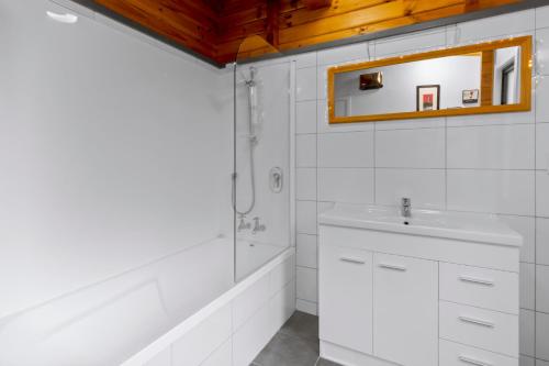 uma casa de banho branca com um lavatório e um espelho em Kereru Cottage, Romantic & Beautiful Log Cabin - Queenstown em Queenstown