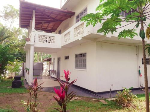a white house with a balcony at Susha Happy One First Floor Apartment in Hikkaduwa