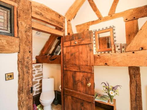 baño con aseo y puerta de madera en The Olde Cow House, en Hughley
