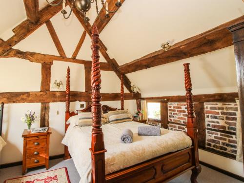 1 dormitorio con cama con dosel en una habitación con techos de madera en The Olde Cow House, en Hughley