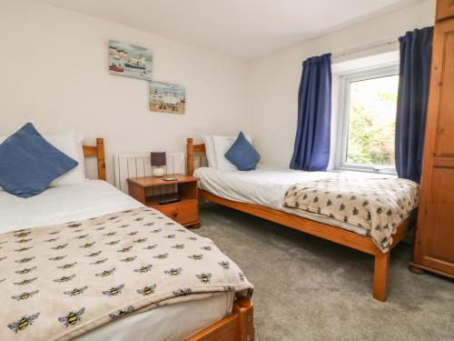 a bedroom with two beds and a window at Pebble Cottage in Redruth